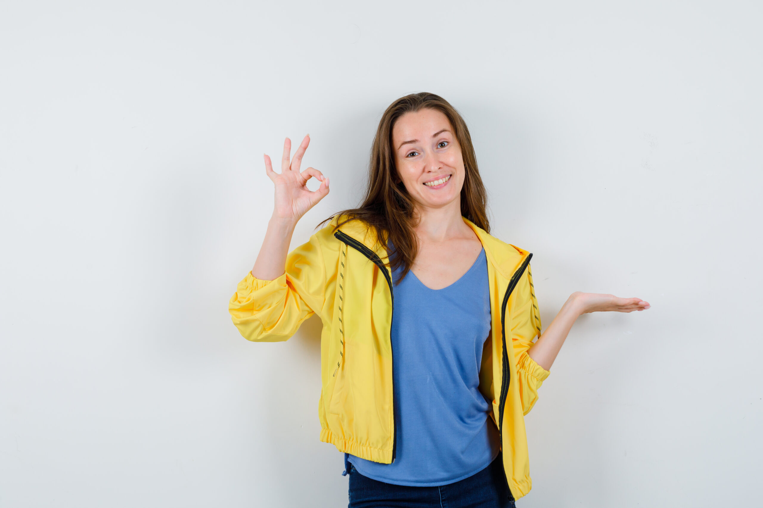 moroccan tours review young lady showing ok sign, spreading palm aside in t-shirt, jacket and looking cheerful , front view.